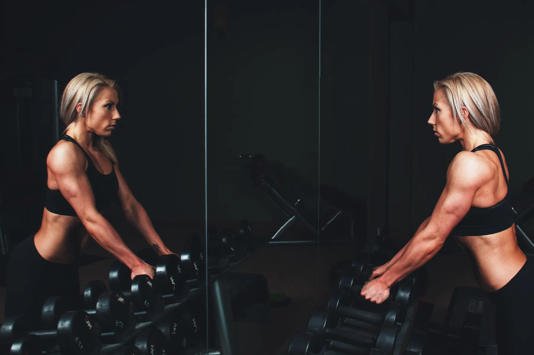A member picking up dumbbells in a dimly lit training floor
